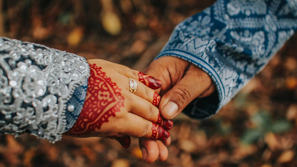 Two hands holding, wearing primitive-style bracelets, soft natural light.